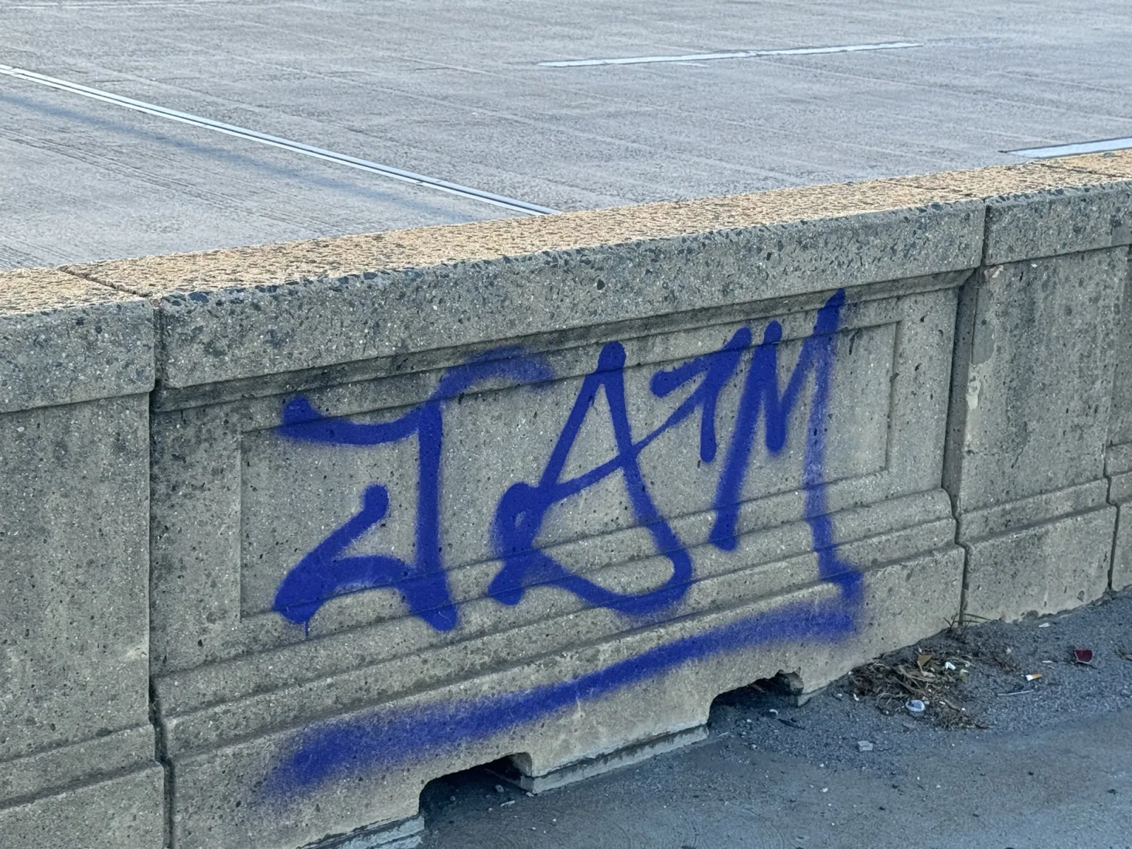 Graffiti tagged across the concrete Jersey barrier wall of the Francis Scott Key Bridge
